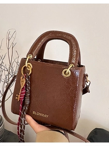 Deep brown square handbag with glossy texture and decorative heart keychain charm