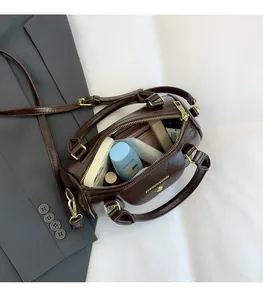 Detail of dark brown leather Boston bag with gold hardware and daily essentials inside