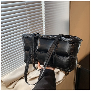 Detail of black quilted puffer tote bag with glossy finish and slim shoulder straps