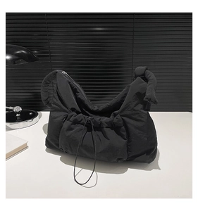 Detail of black quilted nylon shoulder bag with drawstring pocket and bubble strap