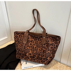Detail of leopard print tote bag featuring metallic studs and brown leather straps