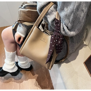 Detail view of khaki bucket bag with lychee grain leather texture and polka dot scarf