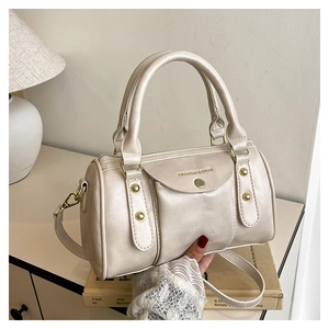 Detailed macro view of cream pillow bag with gold hardware and embossed fashion text