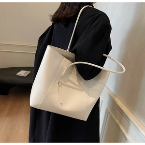 Detail of minimalist cream tote bag with zipper pocket and slender shoulder strap