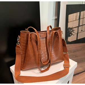 Detailed macro view of brown crocodile embossed tote bag with gold-tone hardware and wide strap