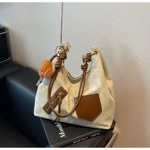 Detailed macro view of canvas tote bag with brown leather pockets and plush bear charm