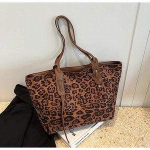 Detail of leopard print tote bag with brown leather handles and metal rivet reinforcement