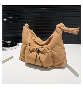 Detailed shot of nylon shoulder bag featuring a knotted handle and functional drawstring pocket