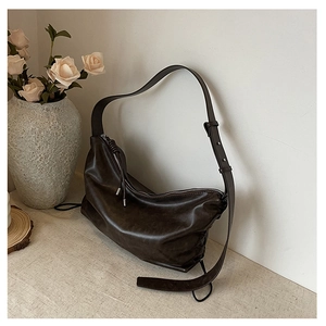 Detailed close-up of dark brown pleated leather shoulder bag with drawstring zipper detail
