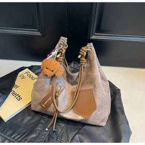 Close-up of vintage brown tote bag with smooth texture and cute teddy bear charm detail