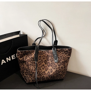 Close-up of leopard print fabric texture and black leather strap on a large tote bag