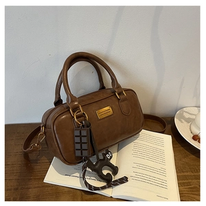 Detail of vintage brown PU leather Boston bag with fashion tags and cat charm accessories