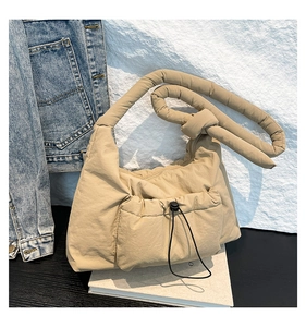 Detail of quilted khaki nylon shoulder bag featuring a drawstring front pocket and knot strap