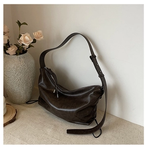 Detail of soft pleated texture and silver buckle on a dark brown hobo shoulder bag