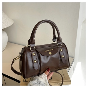Detail of dark brown leather Boston bag showing golden rivets and a smooth zipper closure