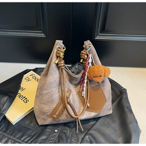 Detail of vintage tote bag with thick rope handles and plush teddy dog charm on leather