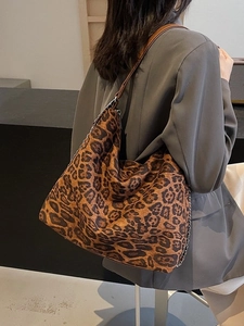 Large leopard print tote bag with brown leather strap worn with a grey blazer