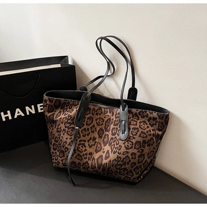 Detail view of large leopard print tote bag with black straps and leopard pattern texture