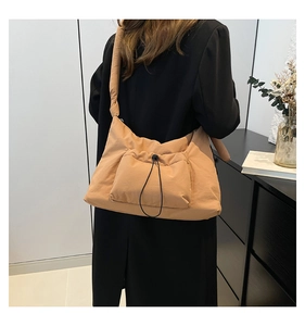 Detail of camel nylon crossbody bag featuring a wide padded strap and front drawstring pocket
