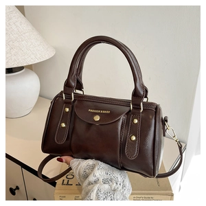 Detailed view of dark brown oil-wax leather handbag with gold rivets and top handles