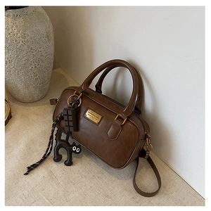 Dettaglio della borsa Boston marrone vintage con placca dorata e ciondolo a gatto