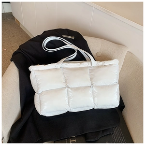 Detail view of large white puffer tote bag with quilted texture on a chair