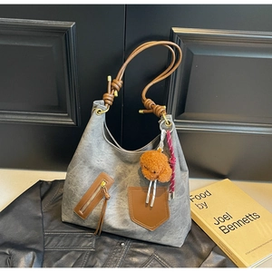 Detail view of large grey hobo bag with brown leather pockets and teddy charm