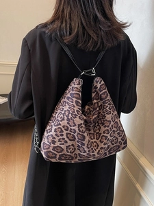 Large leopard print tote bag with black straps and chain on a stylish black coat
