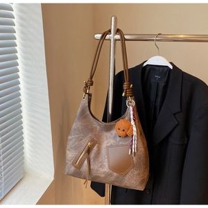 Detail of vintage brown hobo bag with teddy bear charm and soft matte texture