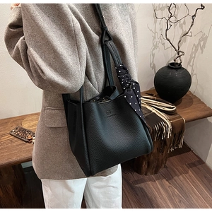 Side view of black lychee grain leather bucket bag with silk scarf on handle