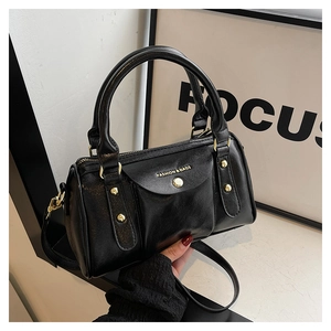 Detail of black glossy pillow bag with golden lettering and stylish round handle