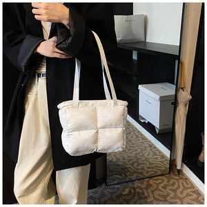 Detail view of a white quilted puffer tote bag with glossy finish and soft padded handles