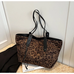 Detail view of leopard print tote bag with black leather straps and ample storage space