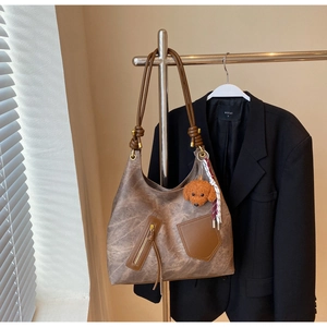 Detail of vintage brown tote bag with zipper pocket and plush dog charm on shoulder strap