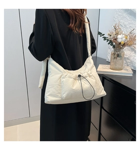 Detailed view of beige nylon dumpling bag with adjustable drawstring pocket on model