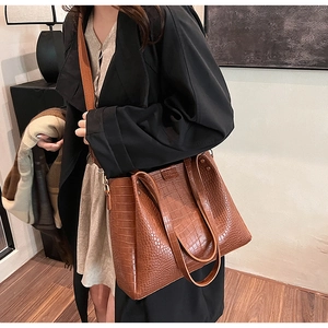 Detail of retro brown tote bag featuring crocodile pattern and adjustable shoulder strap