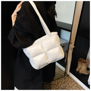 Detail of white quilted puffer tote bag with wide padded strap on shoulder
