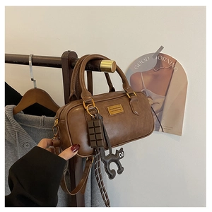 Dettaglio borsa Boston marrone con ciondoli a forma di cioccolato e gatto nero
