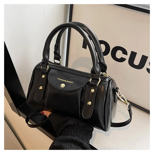 Detail of black glossy bowling bag showing gold rivets and adjustable crossbody strap