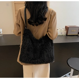 Detail of black plush tote bag with lamb-like fur texture and faux leather shoulder strap