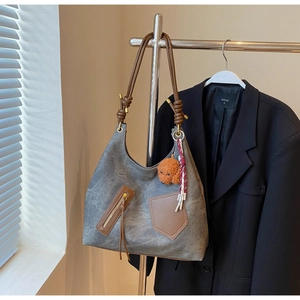 Close-up of gray vintage tote bag with brown zip pockets and cute dog plush pendant