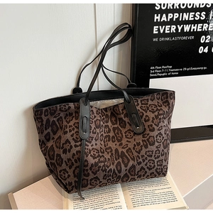 Close-up of large leopard print tote bag with black handles on a minimalist background