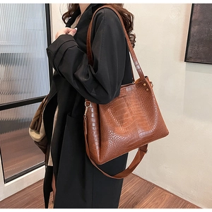 Close-up of brown crocodile embossed leather tote bag featuring a vintage gold metal clasp
