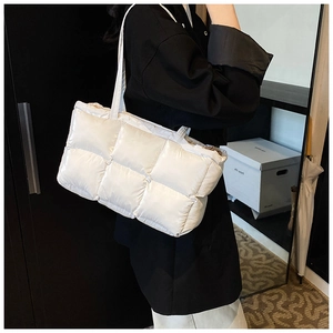 Lifestyle shot of large white quilted tote bag worn on shoulder by a model