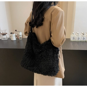 Detail view of a large black plush tote bag styled with an elegant autumn blazer outfit