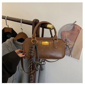 Brown Boston bag detail with cute cat and chocolate charms hanging on a wooden hanger