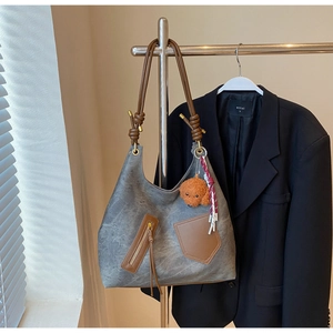 Detail of vintage gray suede hobo bag with brown leather pockets and teddy charm