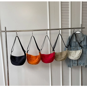 Row of five colorful canvas half-moon crossbody bags with mountain line embroidery