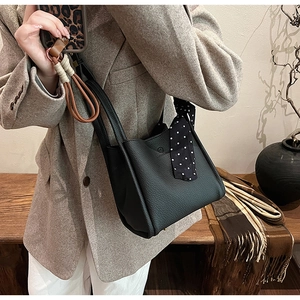 Close-up of black lychee grain leather bucket bag with a stylish polka dot silk scarf