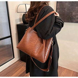 Detailed view of crocodile embossed leather texture on a vintage brown bucket bag